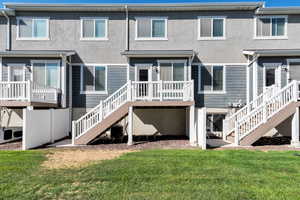 Back of house featuring a lawn, stucco siding, and a deck
