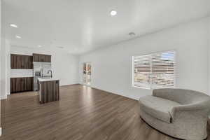 Kitchen featuring dark wood finish cabinets, modern cabinets, recessed lighting, a kitchen island with sink, and stainless steel fridge with ice dispenser