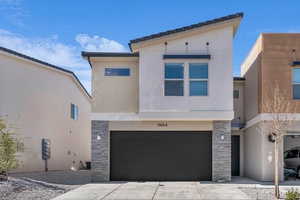 View of front of home with stone siding, stucco siding, an attached garage, and driveway