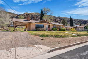 Ranch-style home featuring a chimney, a mountain view, brick siding, dirt driveway, and an attached carport