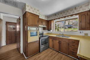 Kitchen with electric stove, light countertops, dark wood finished floors, and plenty of natural light
