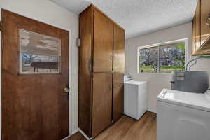 Laundry area with washing machine and clothes dryer, dark wood-style flooring, a textured ceiling, cabinet space, and water heater
