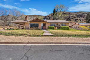 Single story home with a chimney, a carport, a mountain view, and brick siding