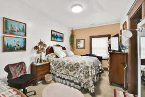 Bedroom with light carpet, ornamental molding, and a textured ceiling