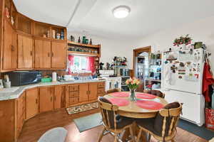 Kitchen featuring wood finish cabinets, white appliances, light countertops, and light wood finished floors