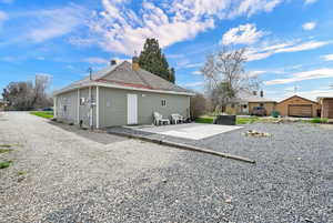 Back of property with an outdoor structure, a patio, a chimney, and a shingled roof