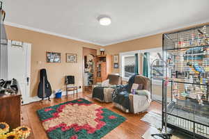 Living room with light wood finished floors, ornamental molding, and arched walkways
