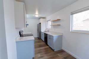 Kitchen featuring light stone countertops, dark wood-style flooring, stainless steel appliances, and open shelves