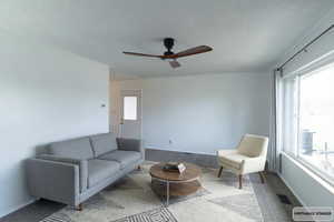 Carpeted living area with a textured ceiling and ceiling fan