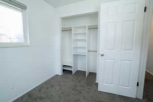 Unfurnished bedroom featuring dark colored carpet and a closet