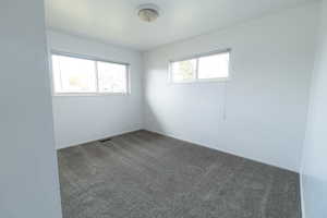 Spare room with dark carpet and baseboards