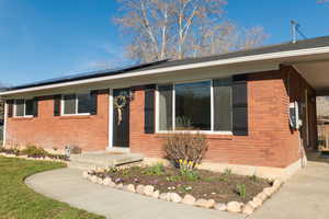 View of front facade with brick siding and roof mounted solar panels