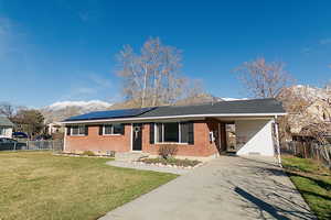 Single story home featuring solar panels, driveway, an attached carport, and brick siding