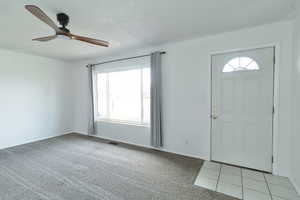 Entryway with light carpet, a textured ceiling, healthy amount of natural light, and a ceiling fan