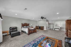 Carpeted bedroom with ceiling fan, wine cooler, recessed lighting, and wet bar