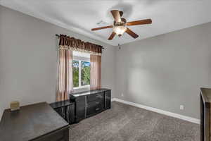 Unfurnished office with dark colored carpet and a ceiling fan