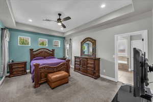 Carpeted bedroom featuring a raised ceiling, a ceiling fan, and recessed lighting