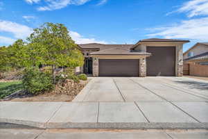 View of front of property with stone siding, a tiled roof, a garage, concrete driveway, and stucco siding