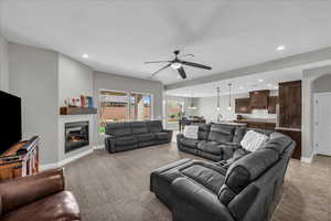 Living area with a glass covered fireplace, a ceiling fan, and suspended lighting