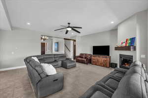 Living area with a ceiling fan, a glass covered fireplace, and suspended lighting