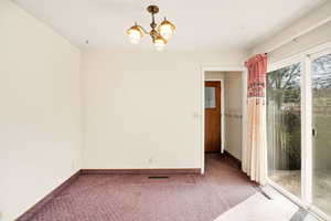 Unfurnished room with suspended lighting and carpet floors