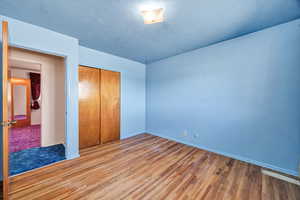 Unfurnished bedroom with wood finished floors and a closet