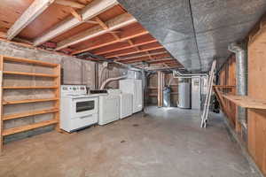 Unfinished below grade area featuring washer and dryer, water heater, freestanding refrigerator, a water softener, and heating unit
