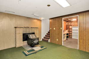 Finished below grade area featuring wood walls, a wood stove, and carpet flooring
