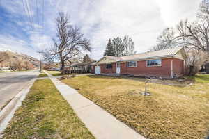 Ranch-style home with a metal roof, a front lawn, brick siding, an attached garage, and a mountain view