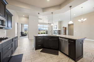 Kitchen featuring light stone countertops, stainless steel appliances, tasteful backsplash, open floor plan, and a tray ceiling