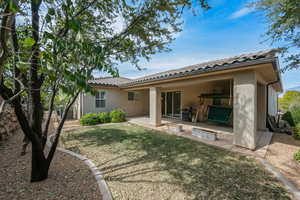 Back of house with a patio area, stucco siding, a yard, and a tile roof