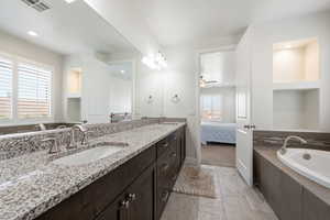 Bathroom featuring double vanity, a garden tub, connected bathroom, ceiling fan, and recessed lighting