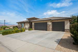 View of front of house featuring an attached garage, stone siding, driveway, and a mountain view
