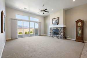 Unfurnished living room with ceiling fan, a fireplace, a mountain view, light colored carpet, and recessed lighting