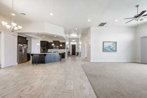 Kitchen featuring open floor plan, a spacious island, a breakfast bar, stainless steel appliances, and suspended lighting