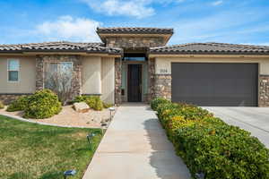 Mediterranean / spanish-style house with stone siding, an attached garage, and stucco siding