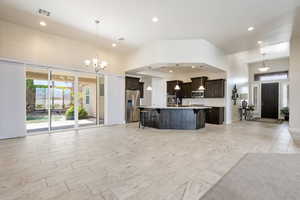 Kitchen with a breakfast bar, open floor plan, dark wood finish cabinetry, stainless steel appliances, and a high ceiling