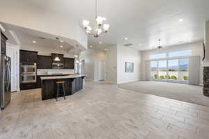 Kitchen featuring open floor plan, a mountain view, a center island with sink, stainless steel appliances, and light stone counters