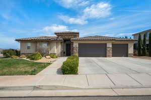 Prairie-style home with stone siding, a garage, stucco siding, concrete driveway, and a front yard