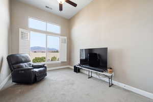 Sitting room with a high ceiling, light colored carpet, and a ceiling fan