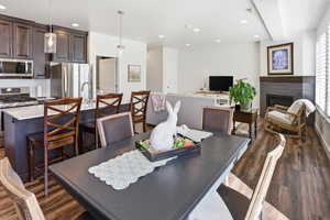 Dining space with dark wood-style flooring, recessed lighting, and a glass covered fireplace