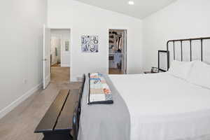 Bedroom featuring lofted ceiling, a spacious closet, and light colored carpet