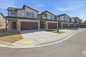 Modern home with stone siding, an attached garage, board and batten siding, and driveway