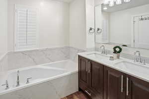 Bathroom with double vanity, a garden tub, and dark wood-type flooring