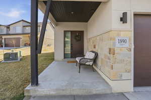 Doorway to property featuring stucco siding, a yard, stone siding, and a porch