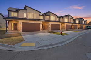 Contemporary house with stone siding, driveway, an attached garage, stucco siding, and board and batten siding