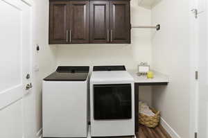 Laundry area with cabinet space, washing machine and clothes dryer, and dark wood-style floors