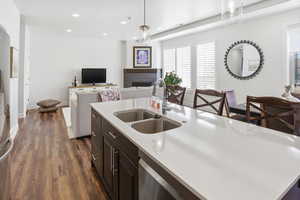 Kitchen featuring open floor plan, a fireplace, dark wood-type flooring, dark wood finish cabinetry, and decorative light fixtures