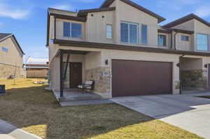 Contemporary home featuring stone siding, a garage, stucco siding, concrete driveway, and a front yard