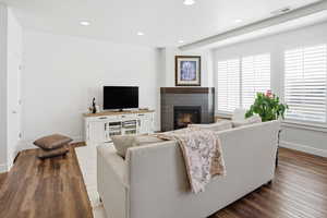 Living area featuring a glass covered fireplace, dark wood-type flooring, and recessed lighting